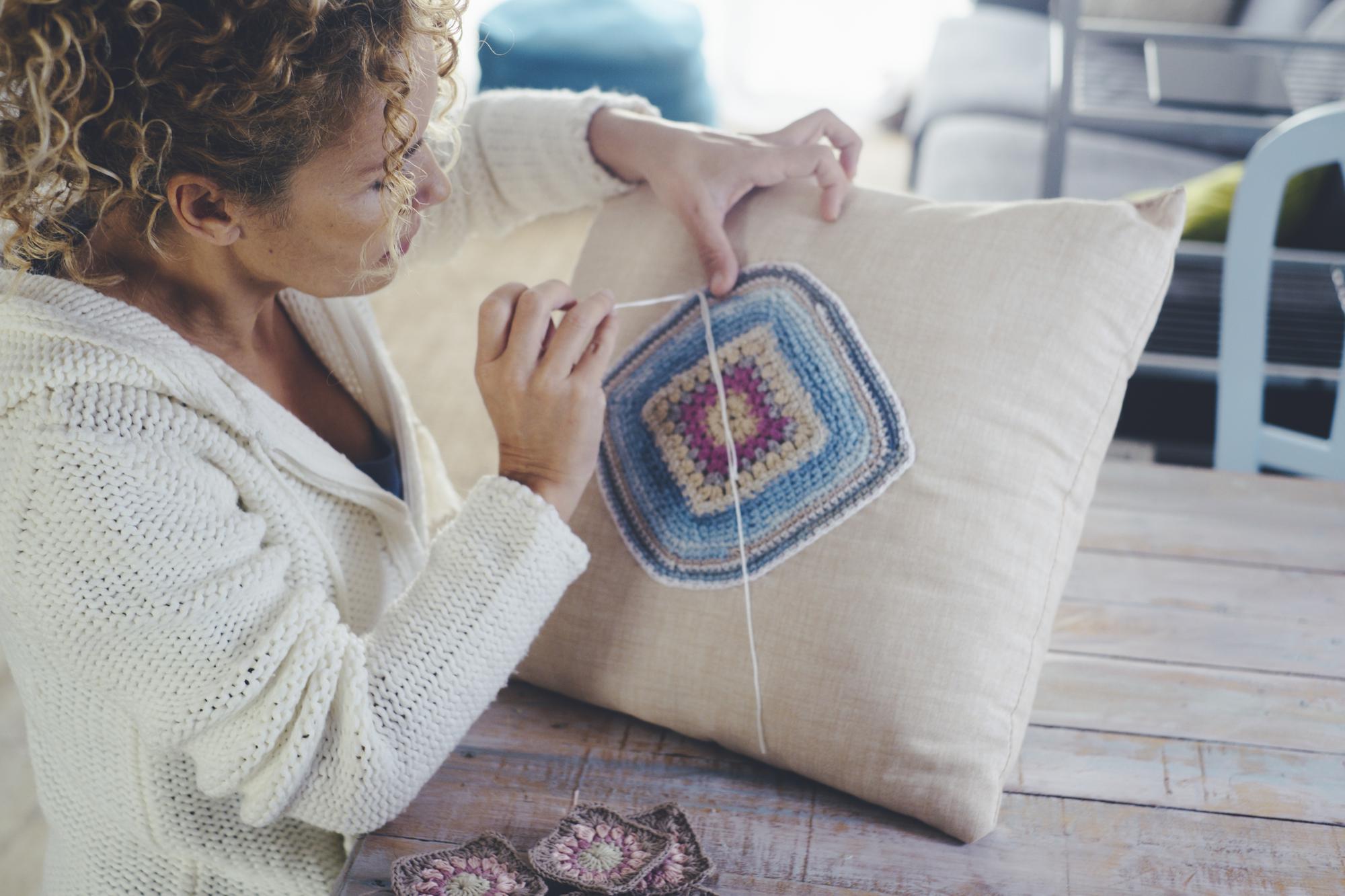 artisan stitching on linen cushion